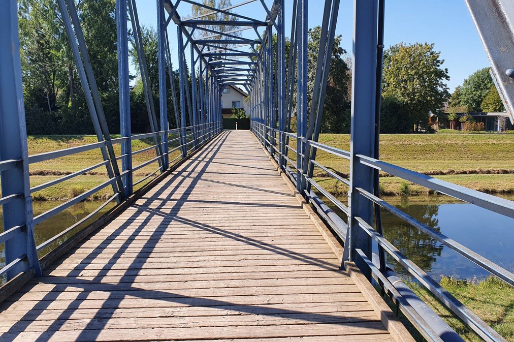 Blick auf die Wiesenbrücke in Wasser mit Stahlfachwerk und Holzbohlen